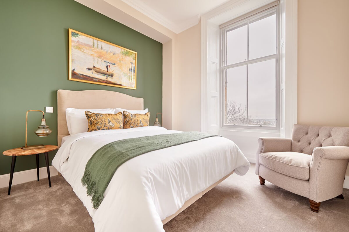 Сучасний біло-зелений інтер'єр: білі стіни, зелений диван, рослини, багато світла.