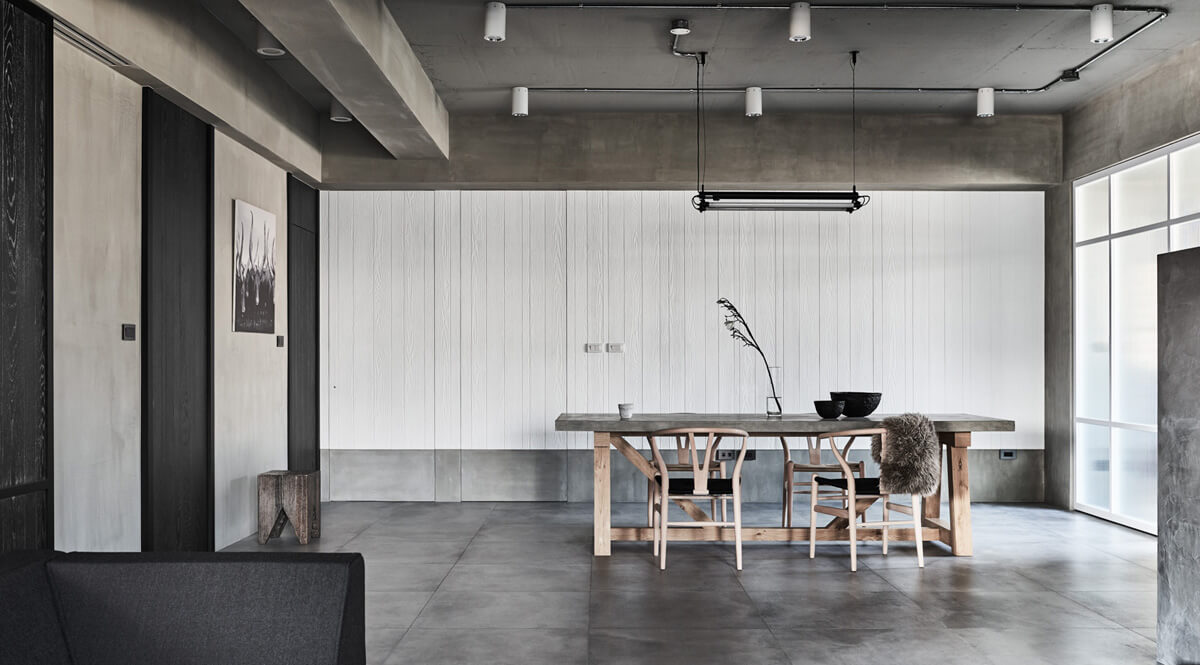 Спальня з бетонною стелею, акцентним освітленням над ліжком та текстильними елементами.