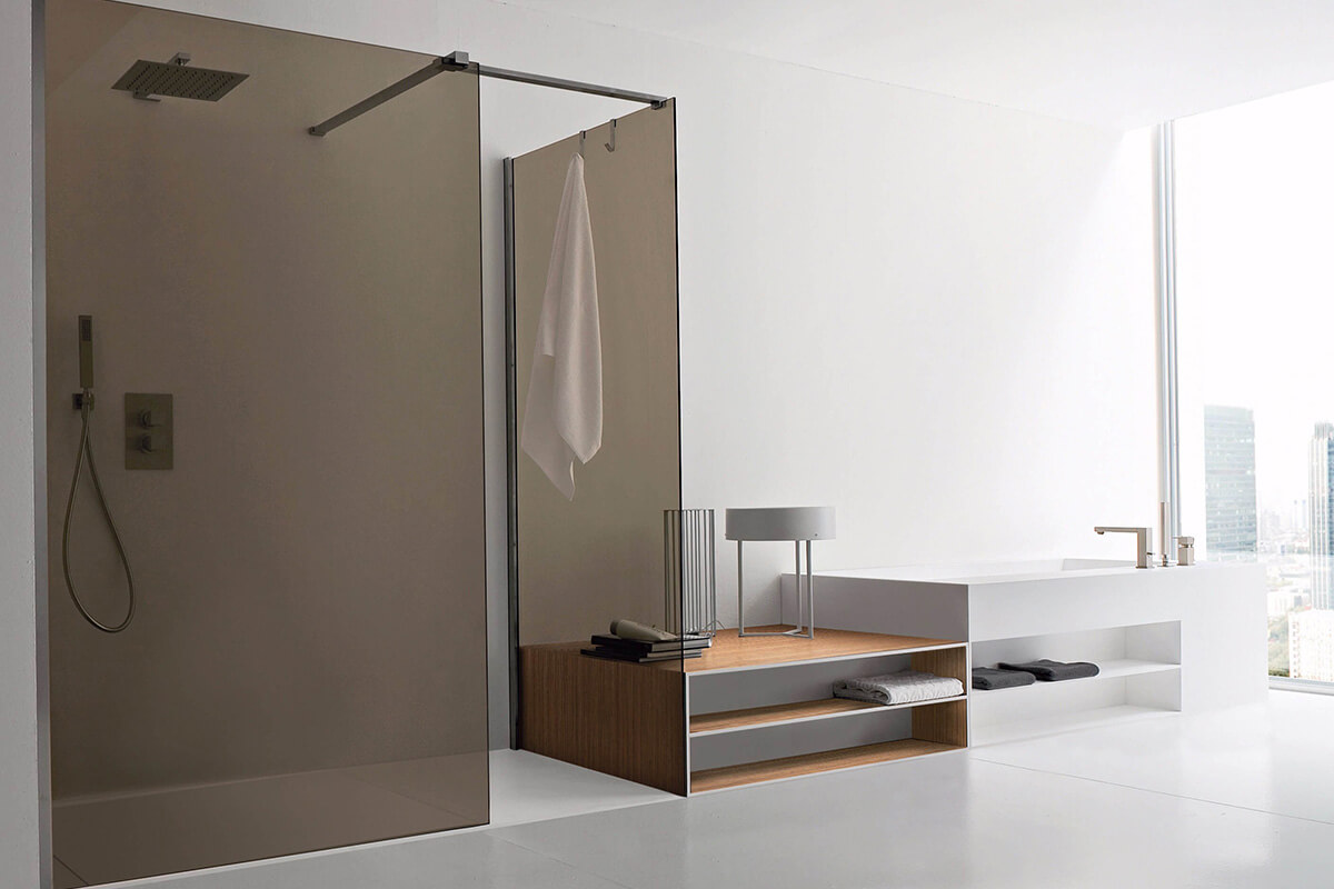 Сучасна скляна душова перегородка у ванній кімнаті з білою плиткою та зеленою рослиною.