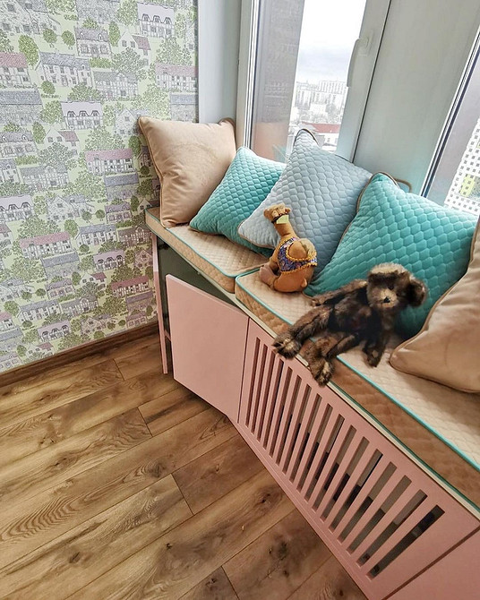 Затишний диван на підвіконні з пледом та подушками, тепла та домашня атмосфера в оселі.