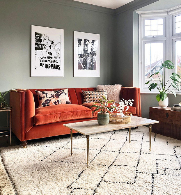 Інтер'єр вітальні з яскравим рожевим диваном та кольоровими подушками в стилі еклектика.