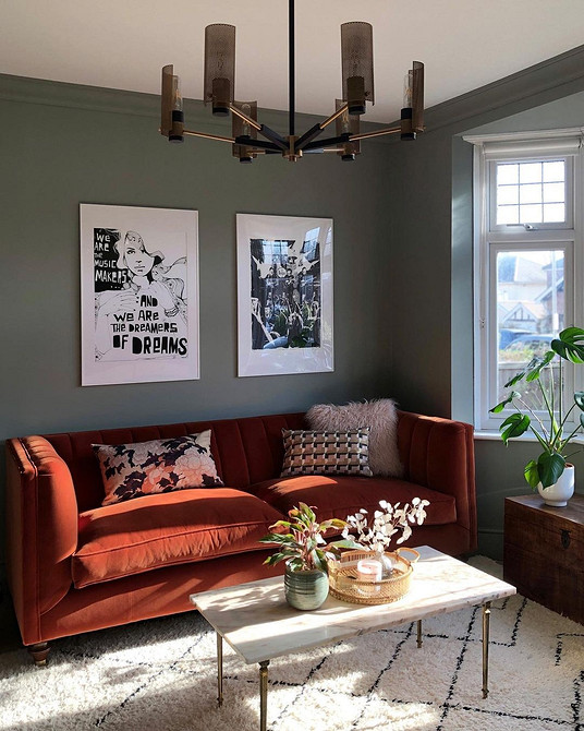 Дизайн вітальні з зеленим диваном, книжковими полицями та килимом в нейтральних тонах.