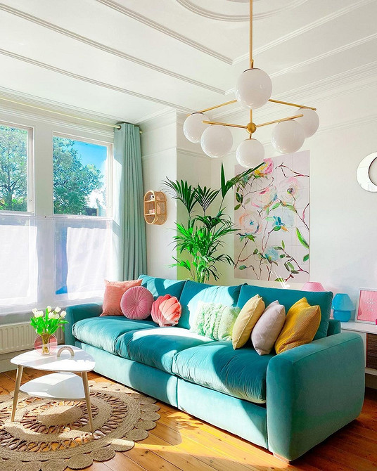 Інтер'єр вітальні з фіолетовим диваном, великим вікном та декоративними подушками.