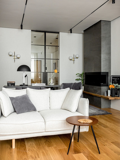 Світлий білий диван Стильний білий диван з дерев'яними ніжками в світлому інтер'єрі вітальні.