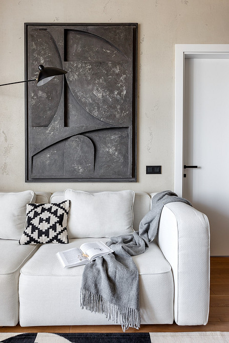 Шкіряний білий диван Білий шкіряний диван в інтер'єрі з каміном та декоративними рослинами в горщиках.