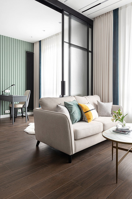 Текстильний затишок Затишний білий диван з текстильною оббивкою, подушками та пледом у світлій вітальні.