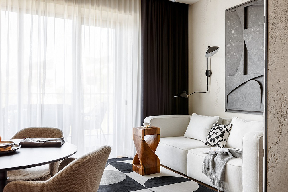 Мінімалізм: білий диван Просторий білий диван з м'якими подушками в мінімалістичному інтер'єрі кімнати.