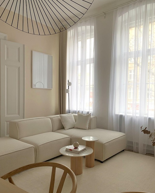 Бежевий диван в інтер'єрі Затишна вітальня з бежевим диваном, світлими шторами та декоративними подушками.