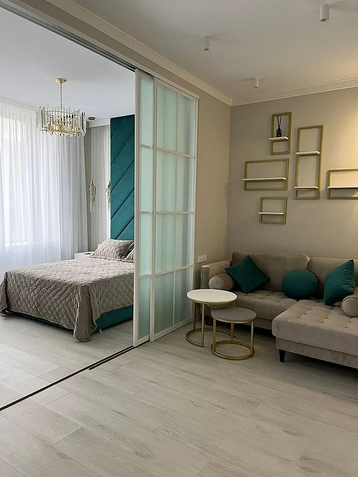 Простора вітальня з великим бежевим диваном, журнальним столиком та світлим декором у 2026