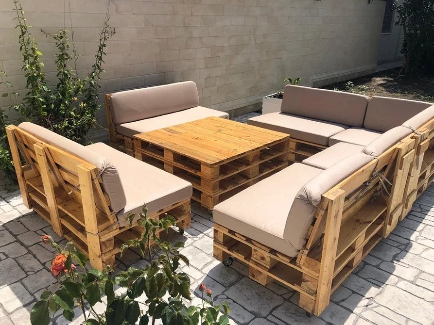 Садові меблі з піддонів: диван ручної роботи на зеленій галявині в саду