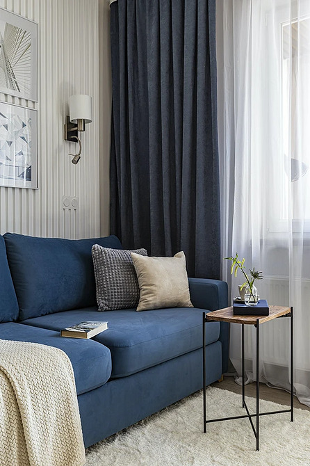 Монохромний інтер'єр вітальні з сірим диваном та декоративними подушками для затишку.