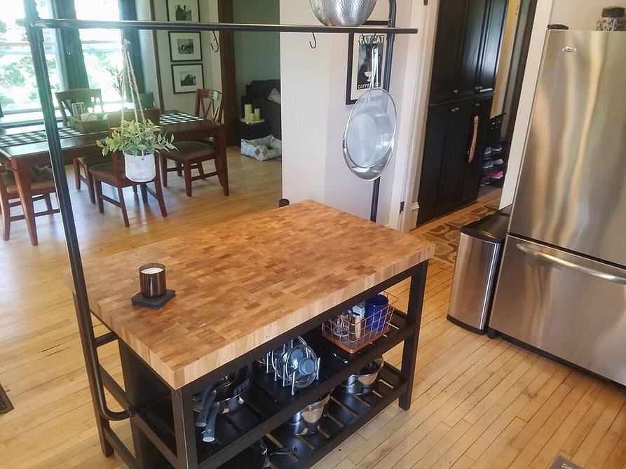 Сучасний мобільний кухонний острів IKEA з дерев'яною стільницею та білими шафами у квартирі-студії.