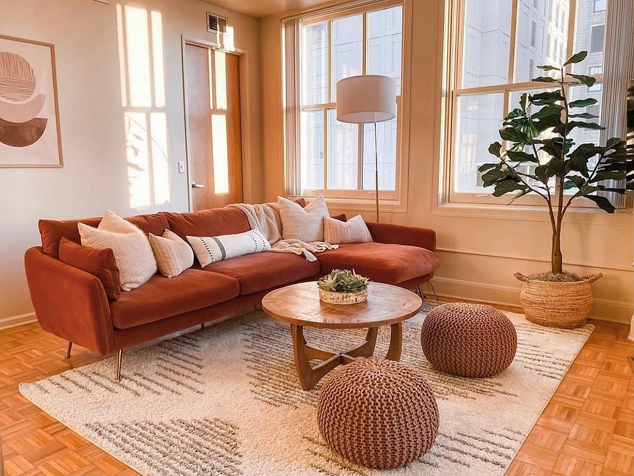 Зелений диван гармонійно поєднаний з природними відтінками в інтер'єрі вітальні.