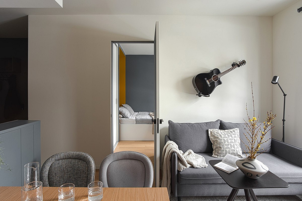 Сірий диван на ніжках з дерев'яними підлокітниками для маленької вітальні.