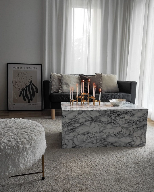 Стильний шкіряний диван світлого кольору в інтер'єрі вітальні з дерев'яними елементами.