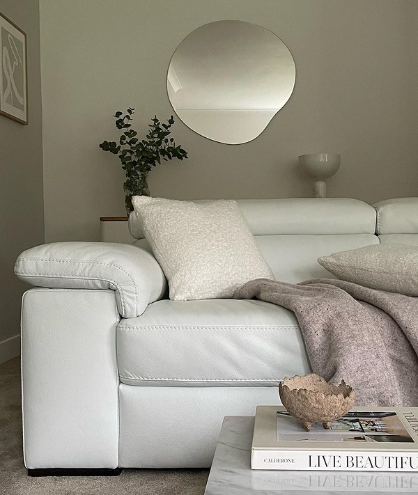 Зелений шкіряний диван в еко-стилі вітальні з рослинами та натуральними матеріалами.