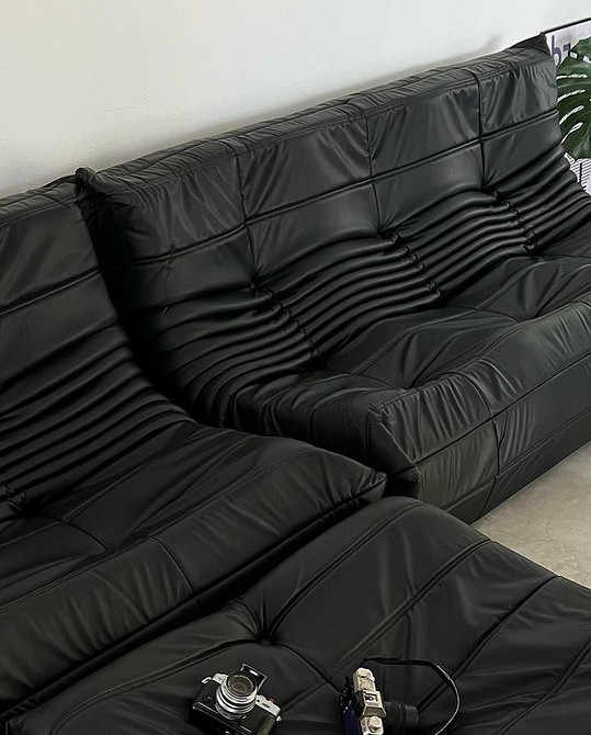 Шкіряний диван бордового кольору в інтер'єрі з каміном та книжковими полицями.