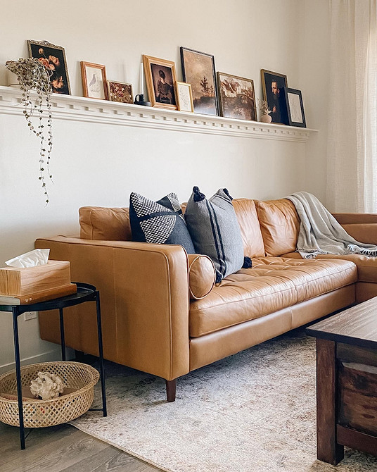 Кутовий шкіряний диван сірого кольору в мінімалістичному інтер'єрі вітальні.