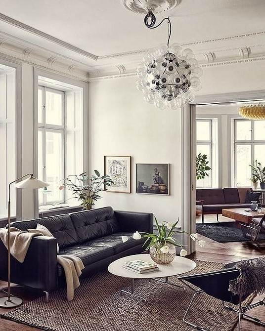 Чорний шкіряний диван в інтер'єрі лофт з цегляною стіною та металевими елементами.