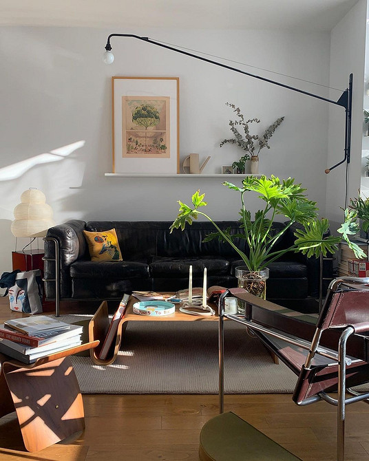 Білий шкіряний диван в мінімалістичному інтер'єрі вітальні з акцентними подушками.