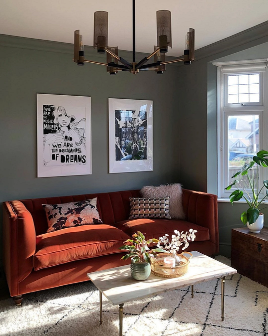 Яскравий червоний диван та килим в тон у вітальні з білими стінами
