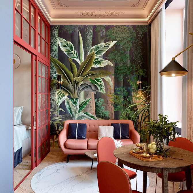 Яскрава вітальня з червоним диваном та зеленими рослинами: свіжий та живий інтер'єр.