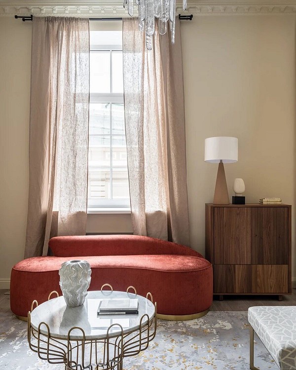 Червоний диван в інтер'єрі з бежевими стінами та дерев'яною підлогою, гармонійне поєднання кольорів.