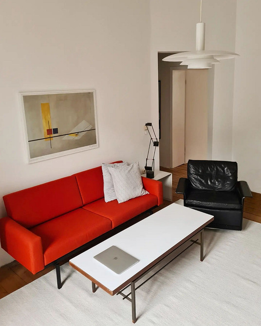 Елегантний червоний диван у поєднанні з білими стінами та золотими деталями