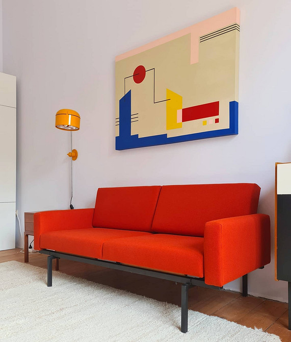 Сучасна вітальня з червоним диваном, яскравими подушками та килимом