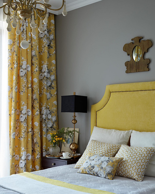 Світла спальня з ліжком з м'якою спинкою, оббитою світлим текстилем.