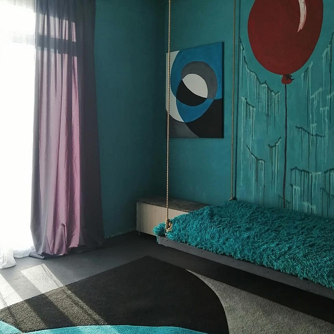 Велика спальня з підвісним ліжком та панорамними вікнами, наповнена світлом.