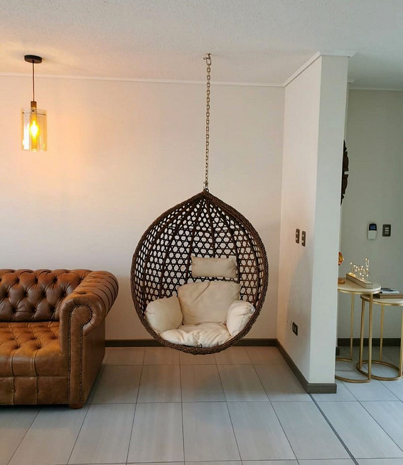 Підвісне крісло гамак з подушками в мінімалістичному інтер'єрі квартири для комфорту.