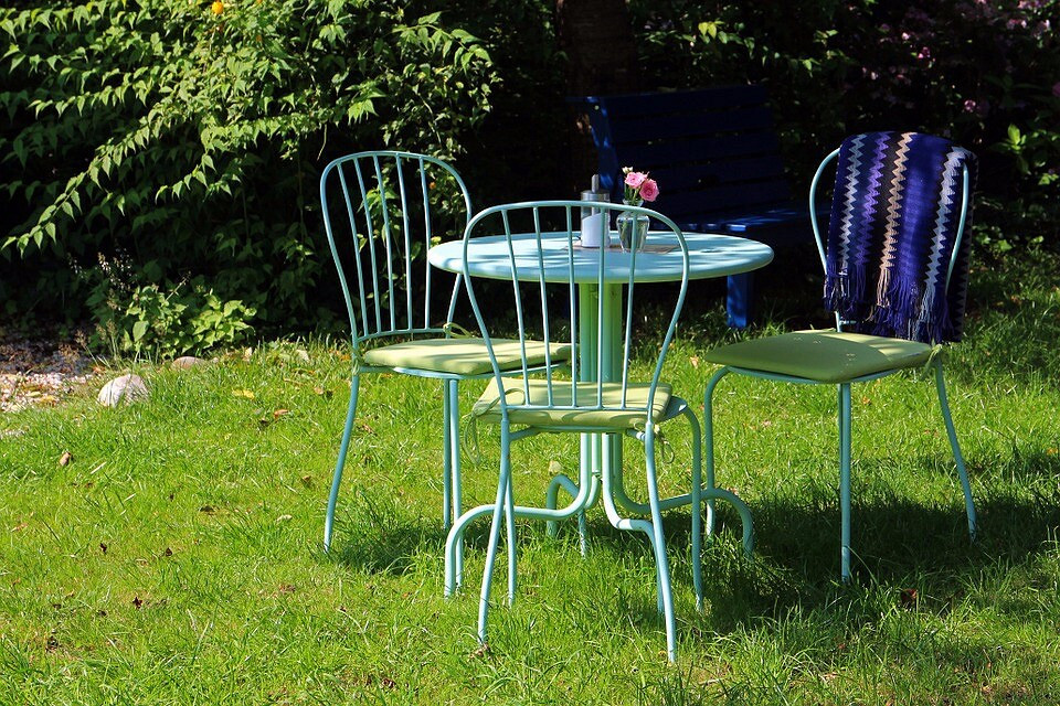 Елегантні садові меблі з кованого металу: стіл і стільці з ажурним візерунком.