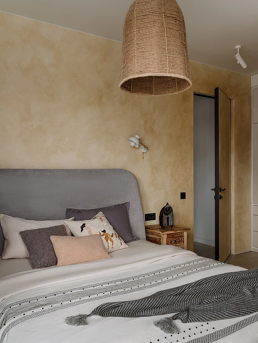 Інтер'єр спальні з сірим ліжком, дерев'яними тумбочками і теплим освітленням.