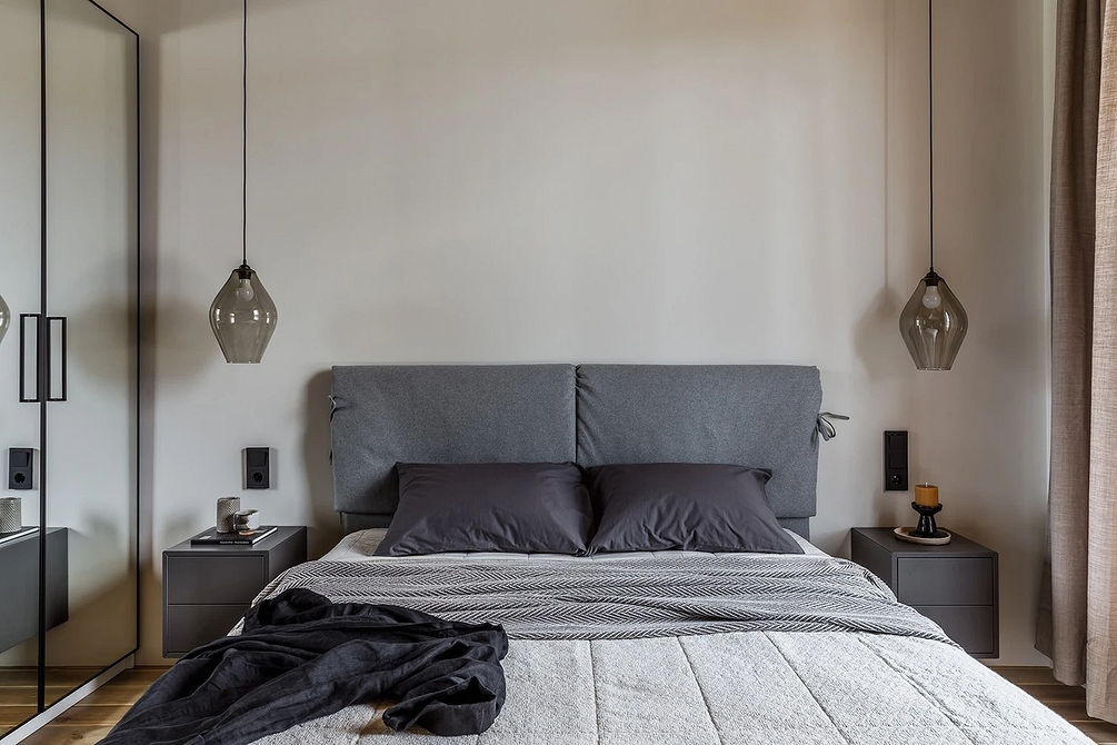 М'яке узголів'я Сіре ліжко з м'яким узголів'ям у спальні з нейтральними відтінками та декоративними подушками.