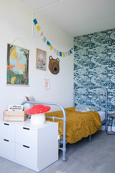 Стильне сіре ліжко з м'яким узголів'ям в спальні з акцентною стіною за ліжком.