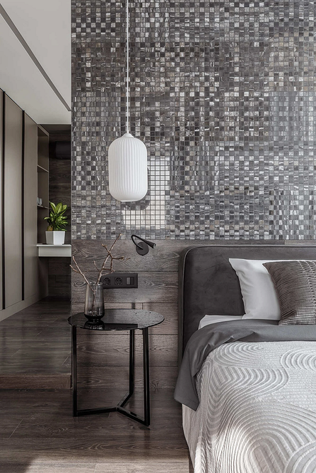 Затишна спальня з великою сірою ліжком та текстилем в теплих тонах.