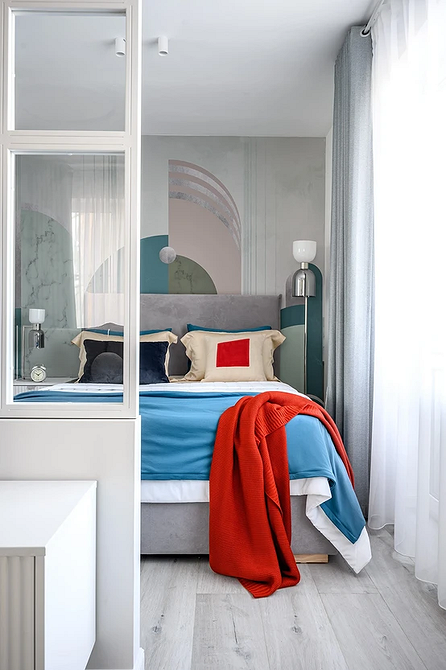 Комфортний сон Затишна спальня з м'яким сірим ліжком, декоративними подушками та теплим освітленням.