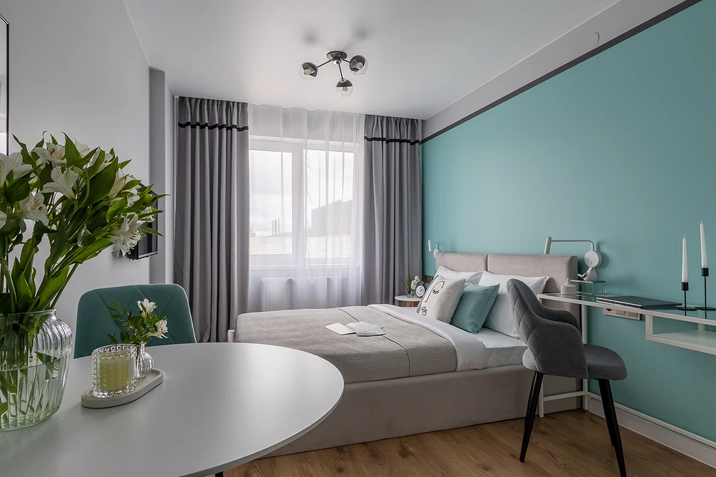 Мистецтво і природа Стильна спальня з сірим ліжком, прикрашена рослинами та художніми елементами декору.