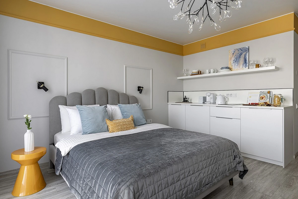 Елегантність у деталях Стильний інтер'єр спальні з сірим ліжком, дерев'яними тумбочками та сучасною лампою.