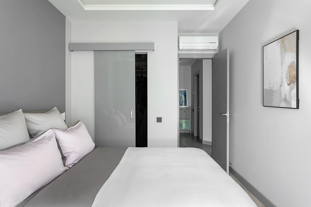 Простора сіра спальня з великим ліжком та акцентним текстилем у стилі лофт.