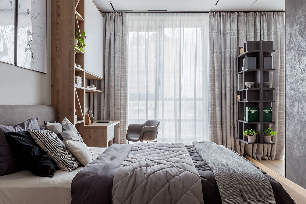 Світло та Стиль Стильна спальня з сірим ліжком, дерев'яною підлогою та сучасними світильниками.