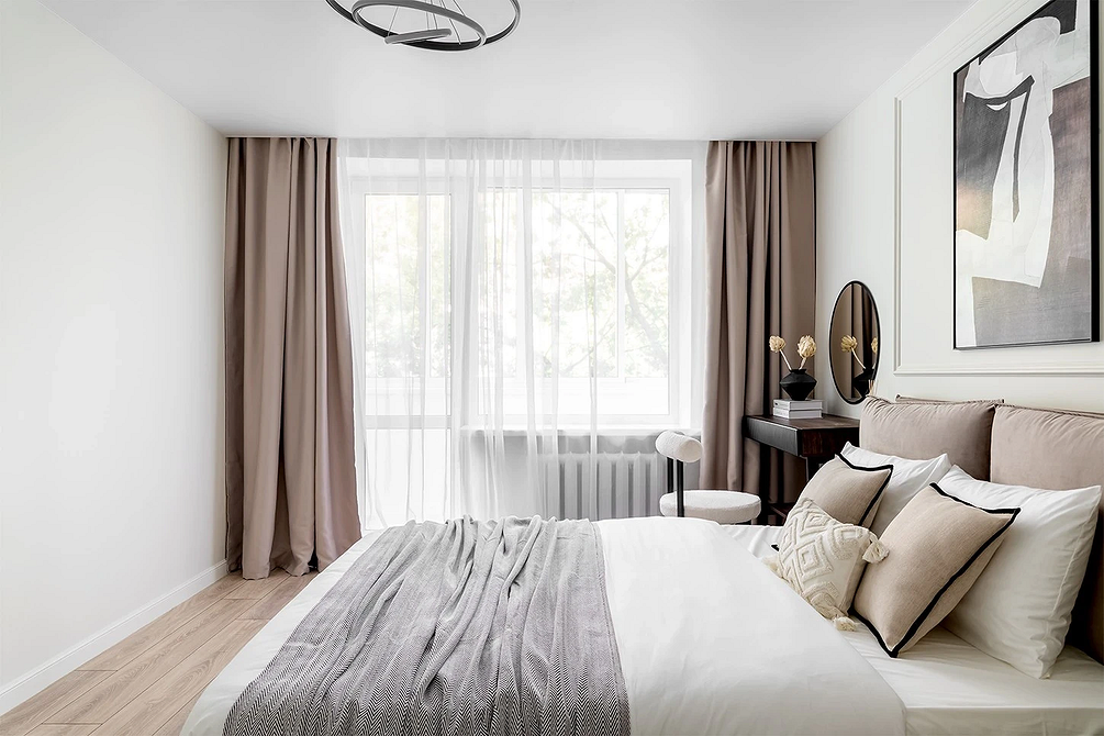 Затишна спальня з сірим ліжком, дерев'яними акцентами і теплим освітленням.