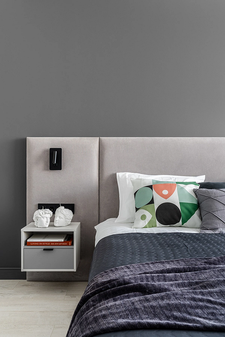 Компактна спальня з невеликою сірою ліжком та мінімальною кількістю меблів.