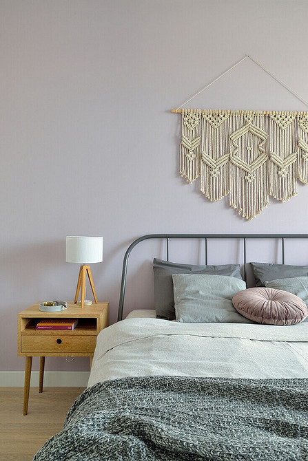 Сучасне сіре ліжко з високим узголів'ям в просторій спальні з великими вікнами.