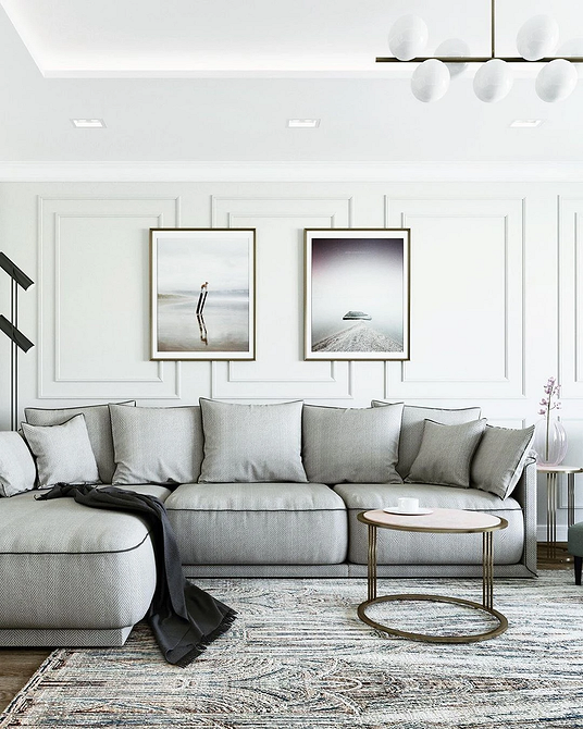 Світлий інтер'єр вітальні з сірим диваном, картинами на стінах та декоративними елементами.