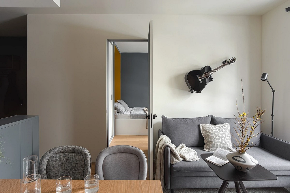 Інтер'єр вітальні з сірим кутовим диваном, дерев'яним столиком та рослинами