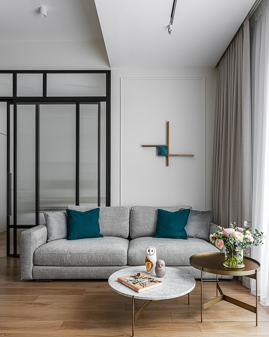 Інтер'єр спальні з сірим диваном, килимом та декоративними елементами