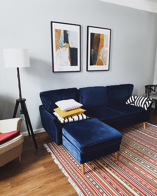 Синій диван та беж Інтер'єр з синім диваном: бежеві стіни, килими та декоративні подушки