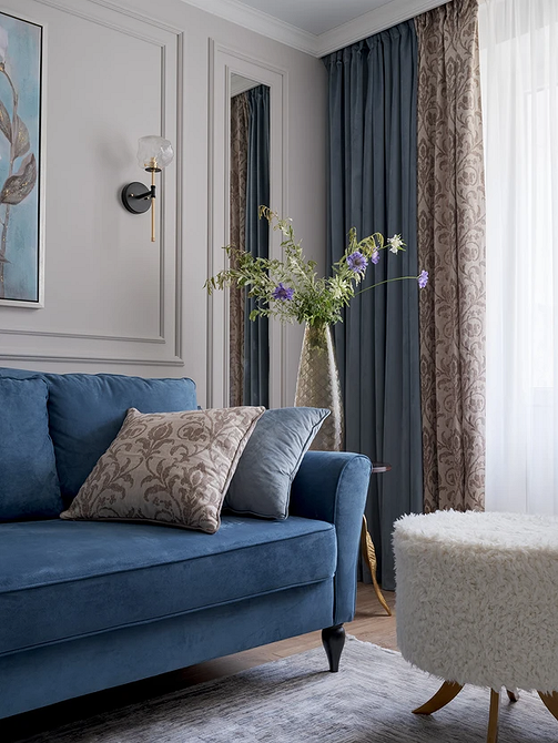 Невеликий синій диван в світлій кімнаті з мінімальним декором, поєднання кольорів.
